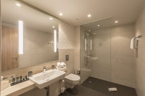 A modern bathroom with a glass-enclosed shower, a white sink, and a toilet. - Holiday Inn Hamburg - Berliner Tor by IHG (Hamburg)