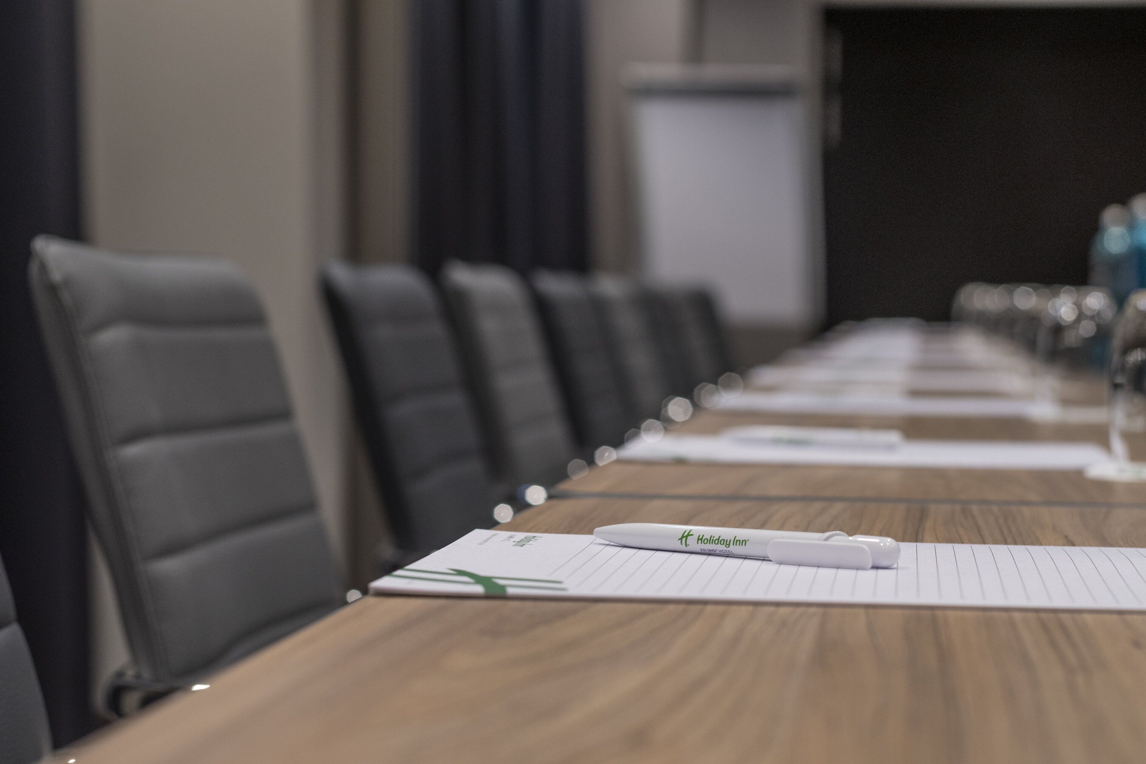 A conference room with a long table, lined with chairs, and a whiteboard in the background.