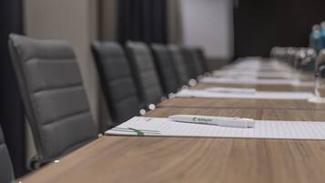 A conference room with a long table, lined with chairs, and a whiteboard in the background.
