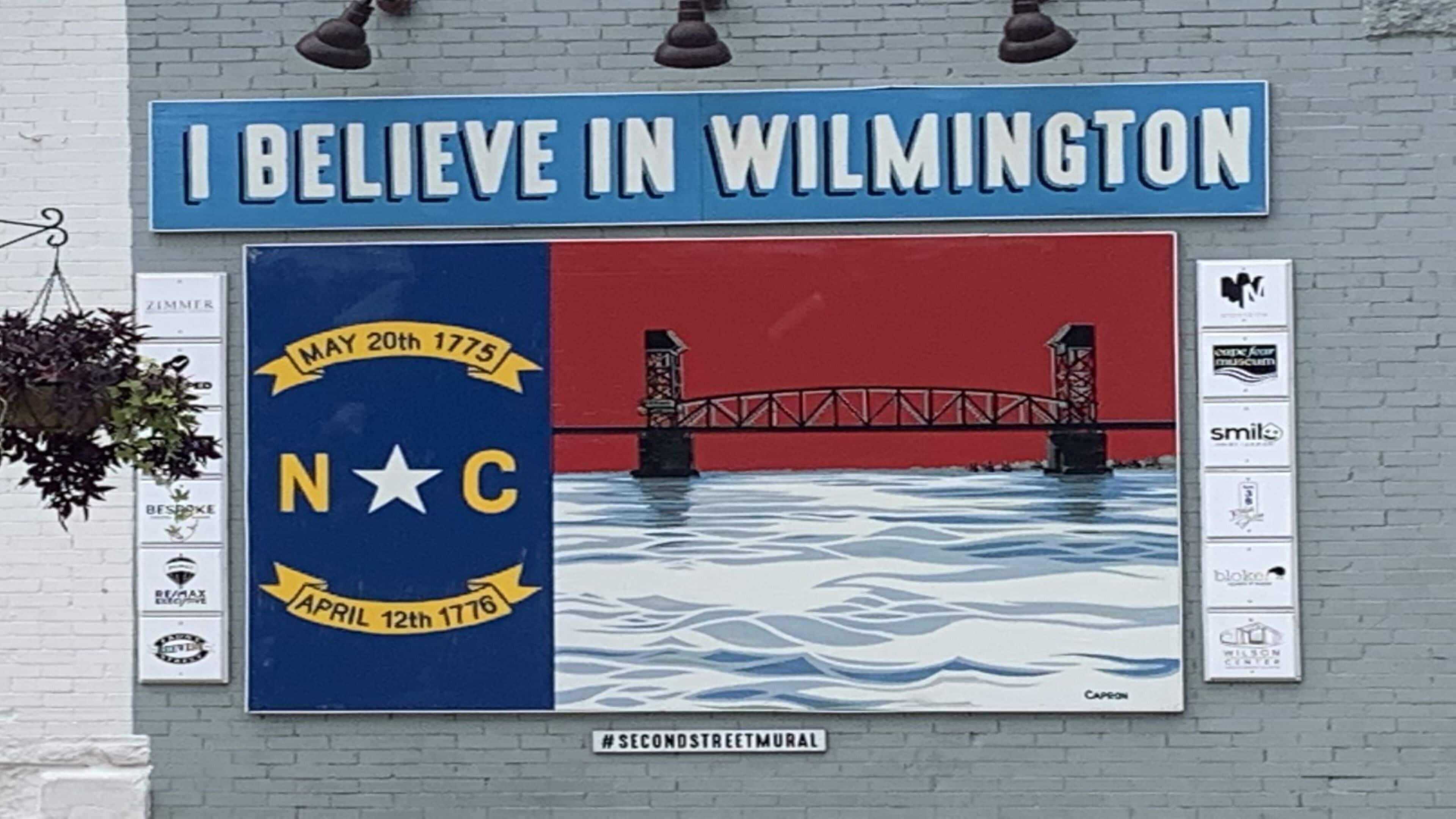 A mural with a bridge and water, and a sign above it that reads "I believe in Wilmington".