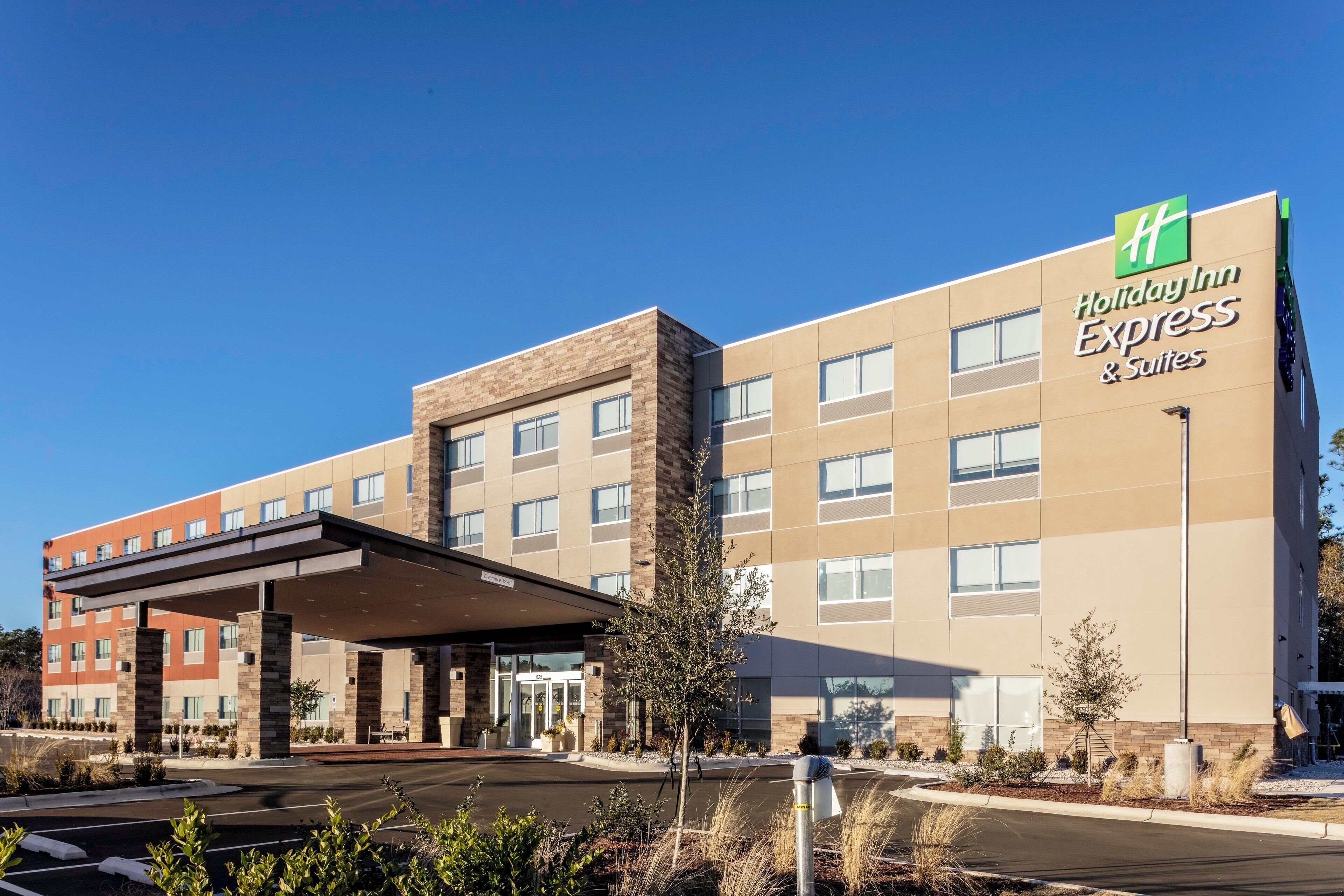 Edificio de Holiday Inn Express Suites con entrada cubierta y estacionamiento.