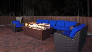 Un espacio al aire libre con asientos, una chimenea, un sofá y una silla.