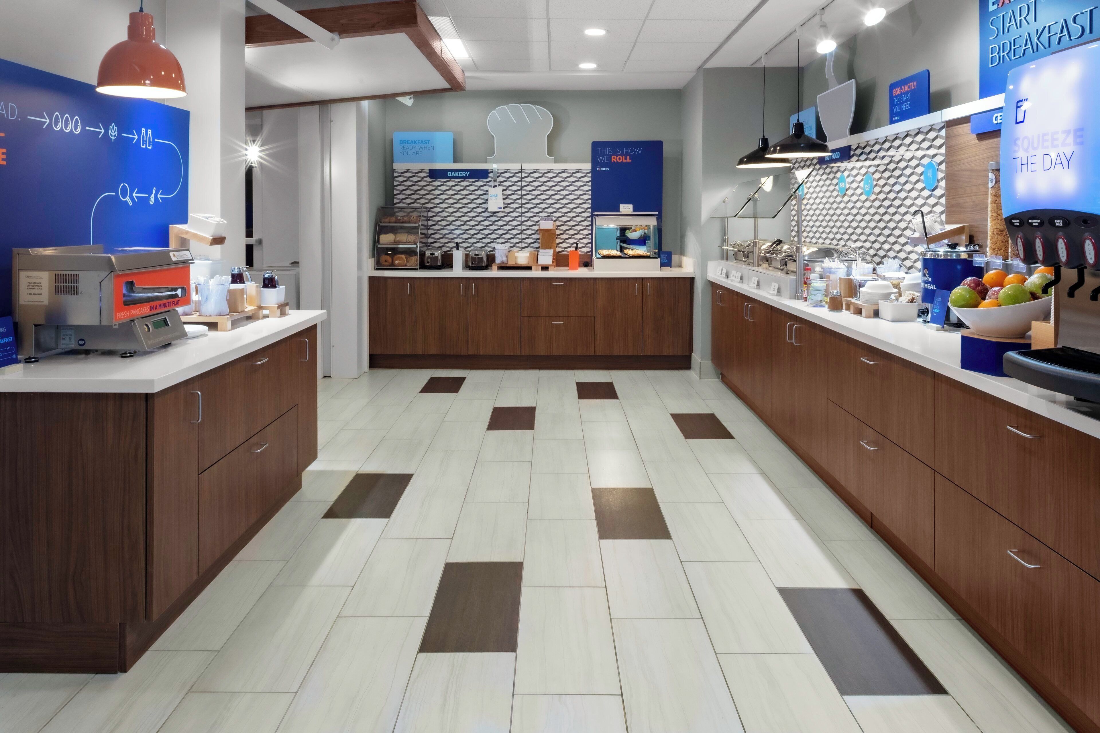 A modern breakfast area with a bakery section, a juice bar, and a counter with various food items.