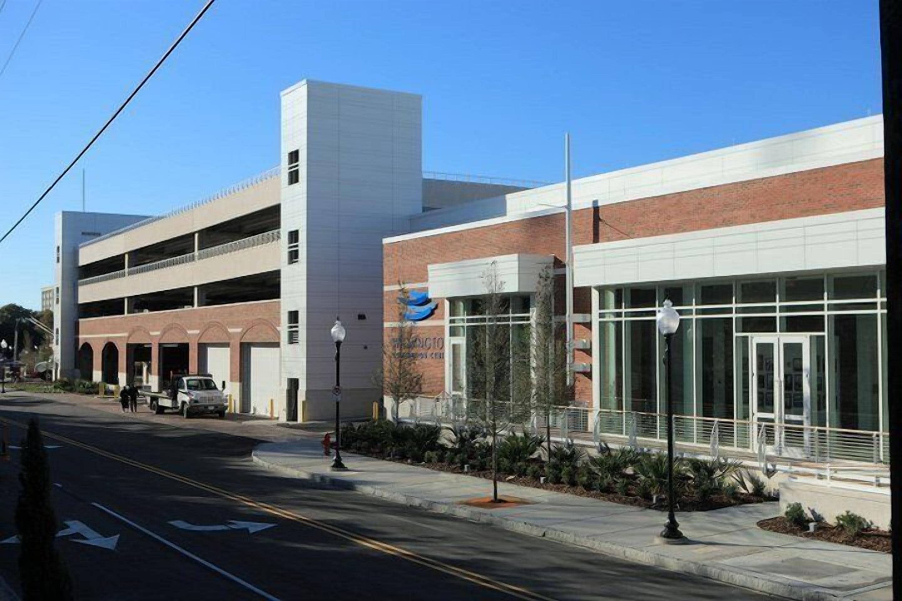A modern building with a parking garage, a covered walkway, and a large glass entrance.