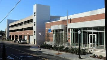 A modern building with a parking garage, a covered walkway, and a large glass entrance.