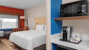 Une chambre d’hôtel avec un lit, un four à micro-ondes posé sur une étagère, une machine à café et une fenêtre donnant sur un paysage agréable.