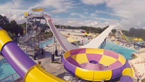 Parque acuático con un tobogán grande, piscina y zona de hidromasaje.