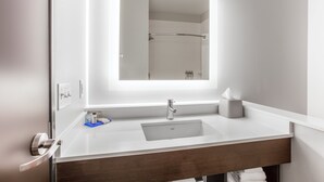 A modern bathroom with a large mirror, a sink, and a towel rack.