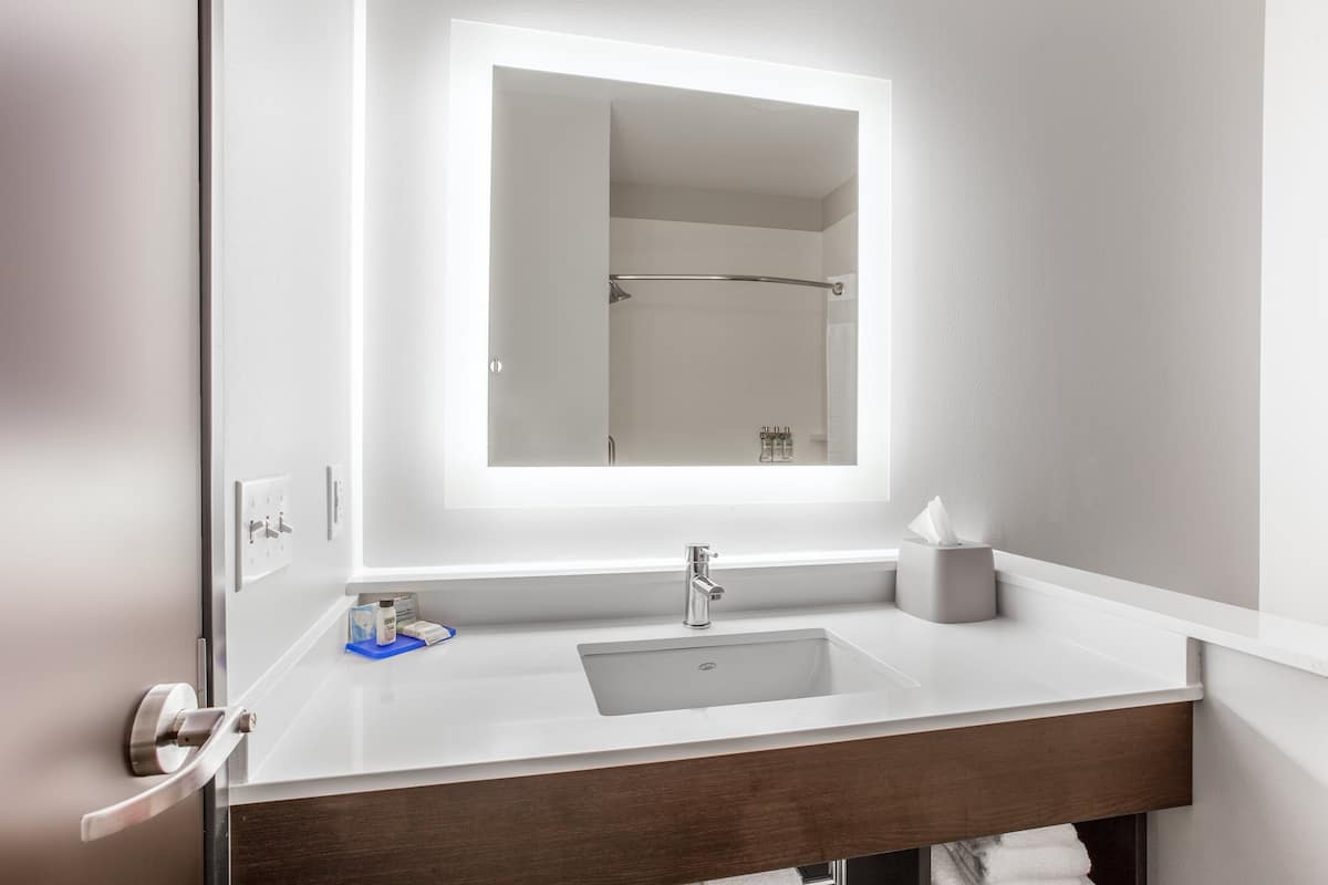 A modern bathroom with a large mirror, a sink, and a towel rack.