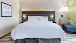 A hotel room with a large bed, bedside tables, a desk, a chair, and a wall-mounted lamp.