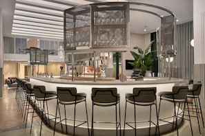 A modern bar area with a circular seating arrangement, a central decorative structure, and a visible bar counter with various items.