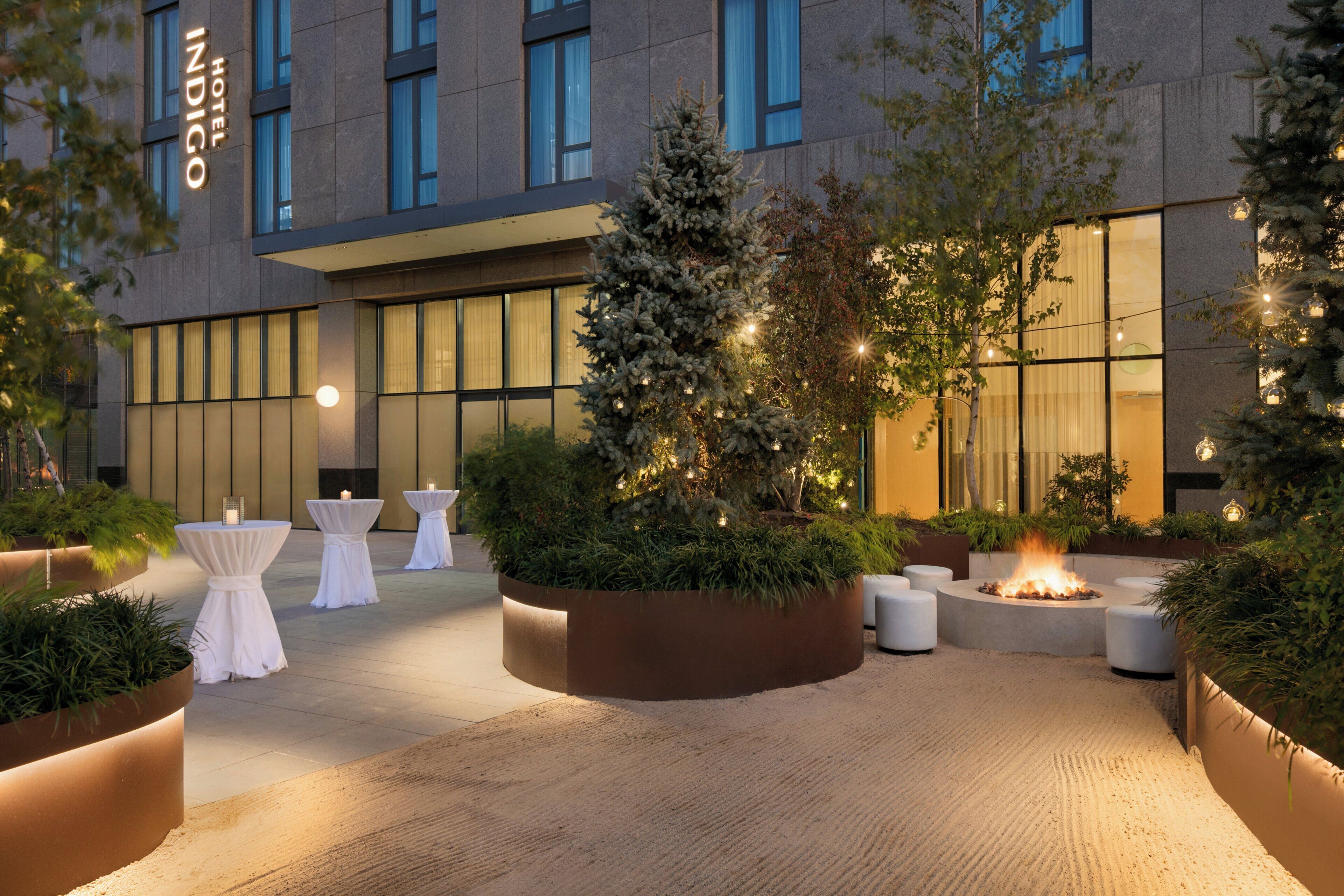 A hotel courtyard with outdoor seating, a fire feature, and a Christmas tree.