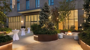 A hotel courtyard with outdoor seating, a fire feature, and a Christmas tree.