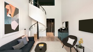 A modern living room with a dark sofa, a coffee table, and a spiral staircase leading to an upper level. - Hotel Indigo Williamsburg - Brooklyn by IHG (Brooklyn)