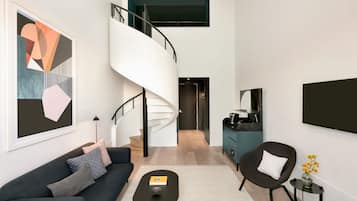A modern living room with a dark sofa, a coffee table, and a spiral staircase leading to an upper level.
