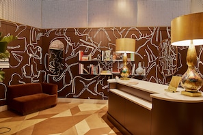 A reception area with a modern design, featuring a sofa, a reception desk, and a decorative lamp.
