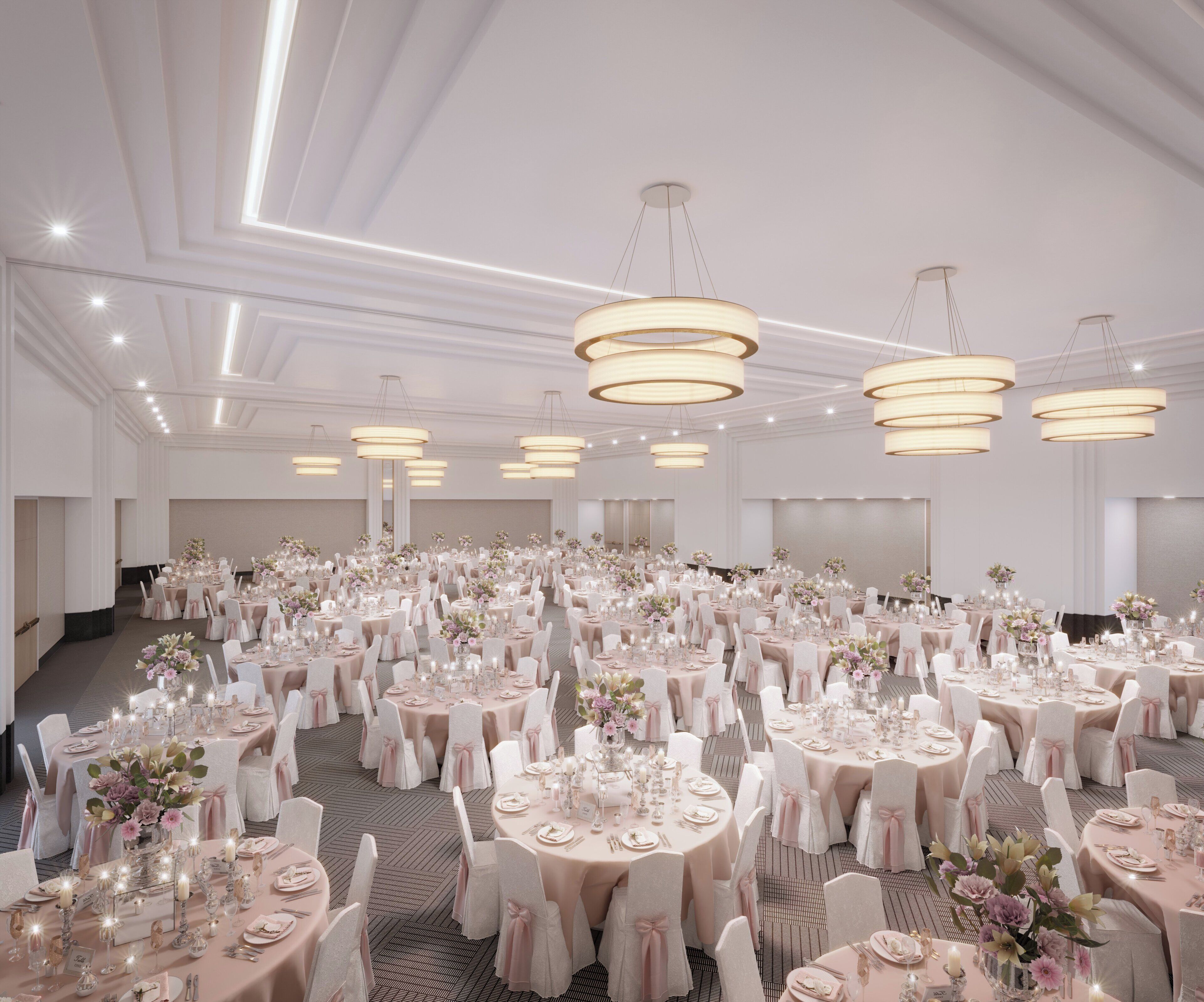 A large banquet hall with round tables, white chairs, and hanging chandeliers.