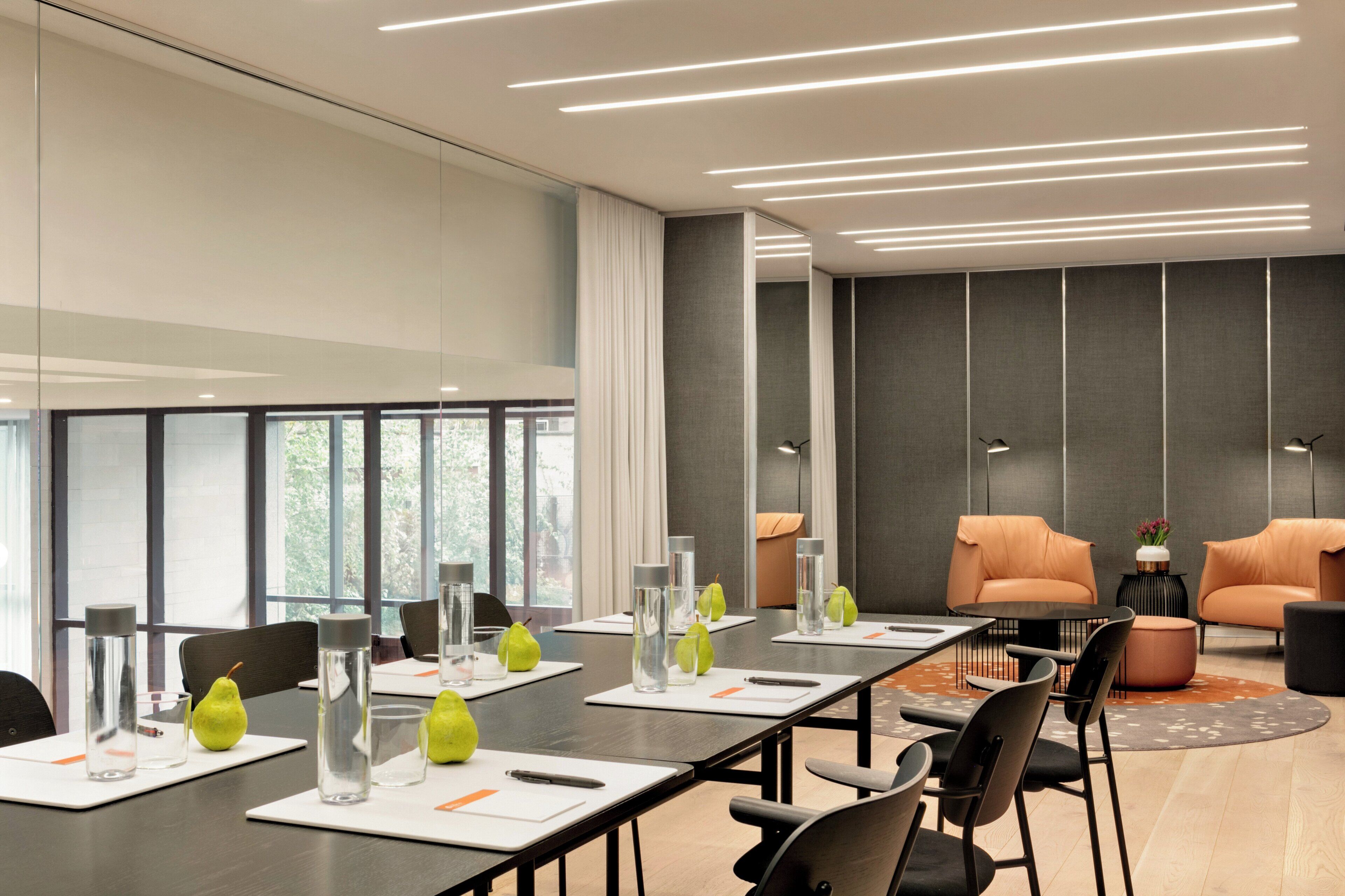 A modern conference room with a long table, chairs, and water bottles.