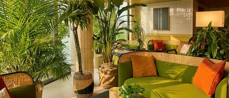 A modern living room with a green sofa, a black coffee table, and various potted plants.
