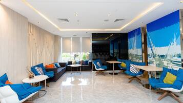 Un área de lounge moderna con una variedad de opciones de asientos, incluyendo sofás y sillones, una mesa de centro y vistas al exterior a través de amplios ventanales.