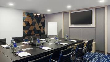 A conference room with a long table, chairs, water bottles, name tags, and a whiteboard.