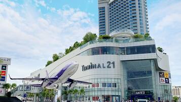 Un edificio moderno con un llamativo letrero 'Terminal 21', que presenta un diseño único de ala de avión en su fachada.
