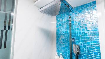 A bathroom with a shower, a blue tiled wall, and two bottles of Dove body wash.