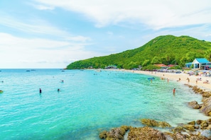 A beach with clear turquoise water, a sandy shore, and a lush green hill in the background. - Holiday Inn Express Pattaya Central by IHG (Pattaya)