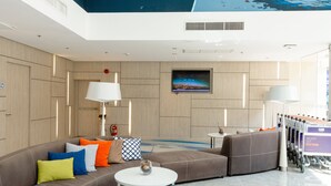 Een moderne hotel lobby met een grote bank, een ronde tafel en een televisie aan de muur.