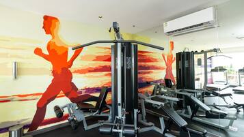 A gym with exercise equipment and a mural of a running woman.