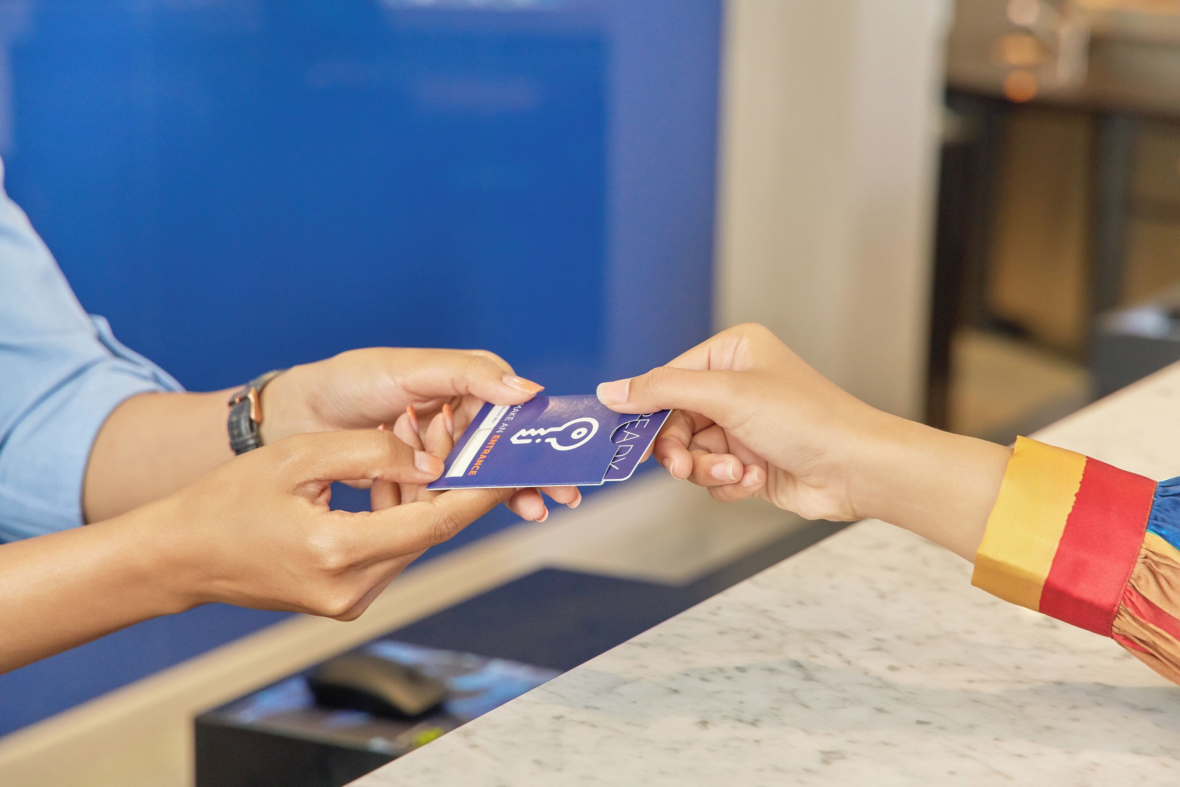 A person handing over a blue card to another person at a counter.