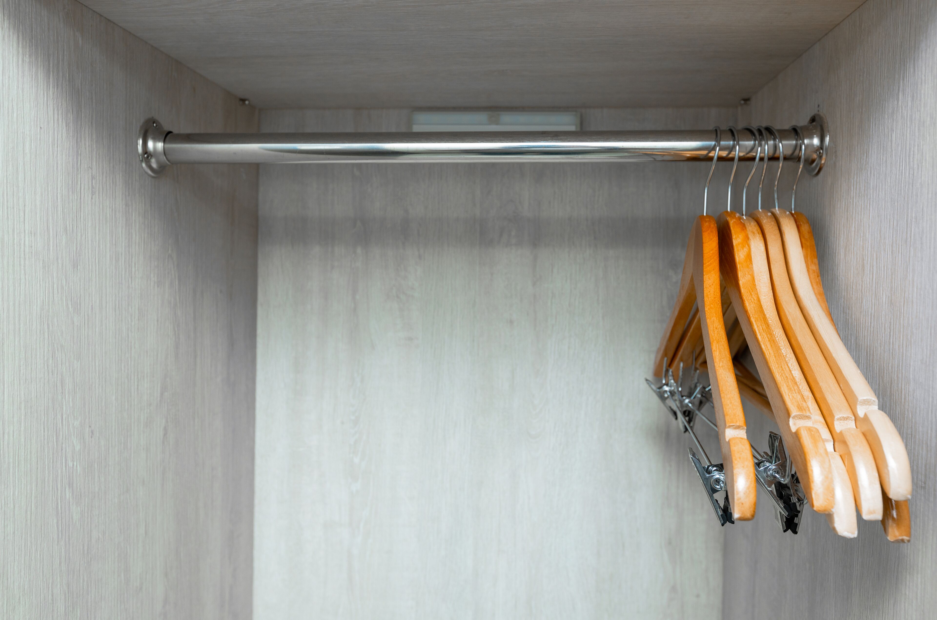 Een kast met een metalen stang en houten kleerhangers.