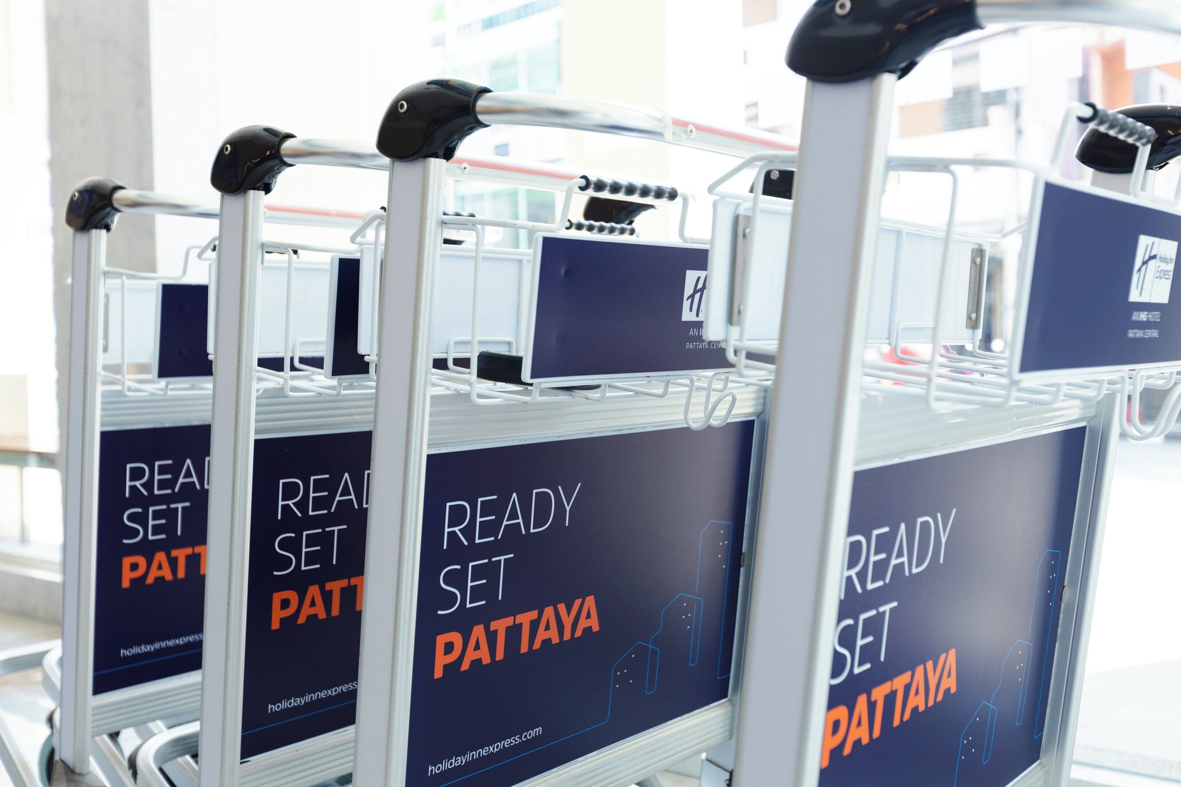 A row of luggage carts with 'READY SET PATTAYA' signage, indicating a location near Pattaya.