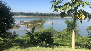 Un espacio cubierto de césped con vista a un río y colinas distantes.