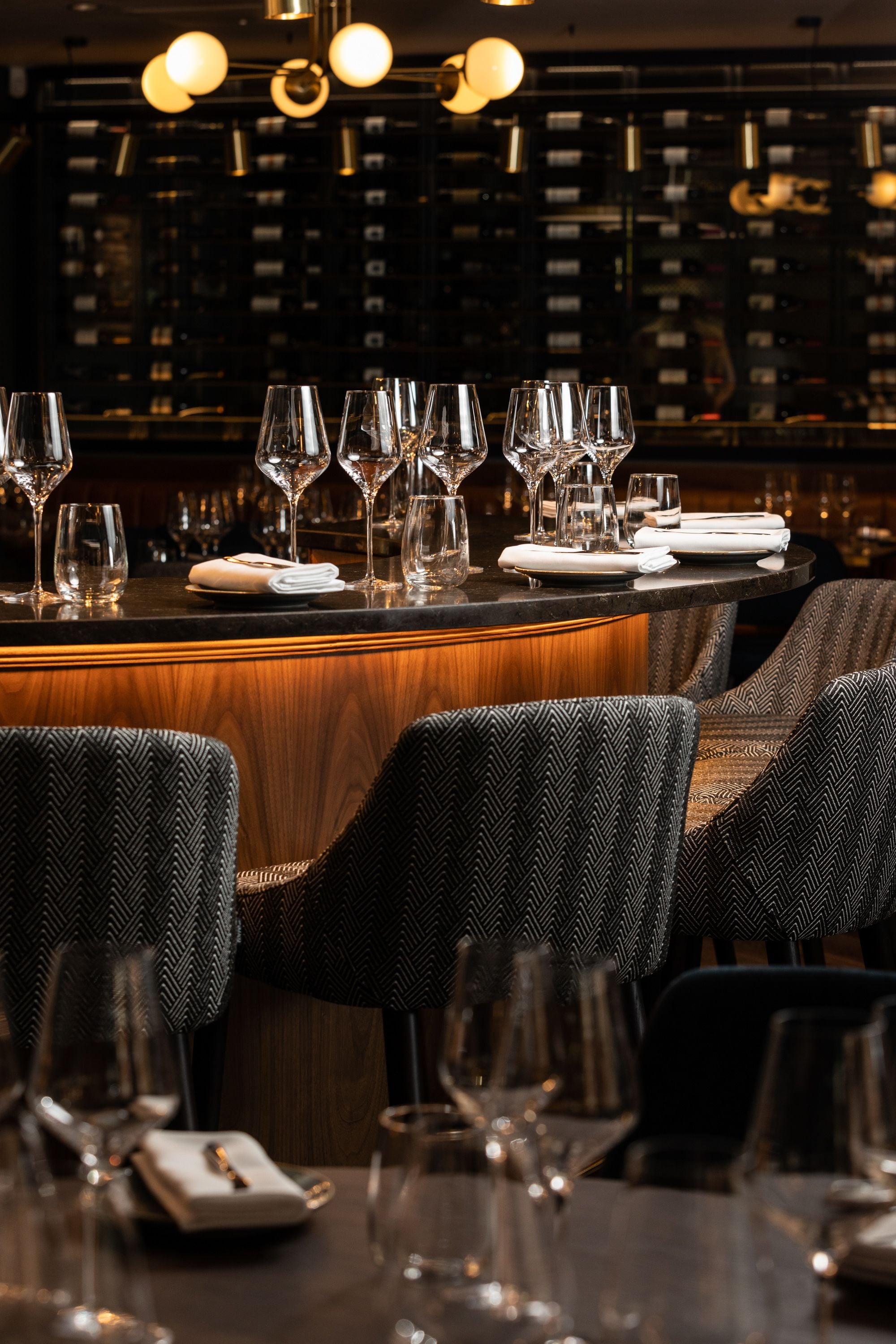 A bar area with multiple wine glasses and plates set up for service.