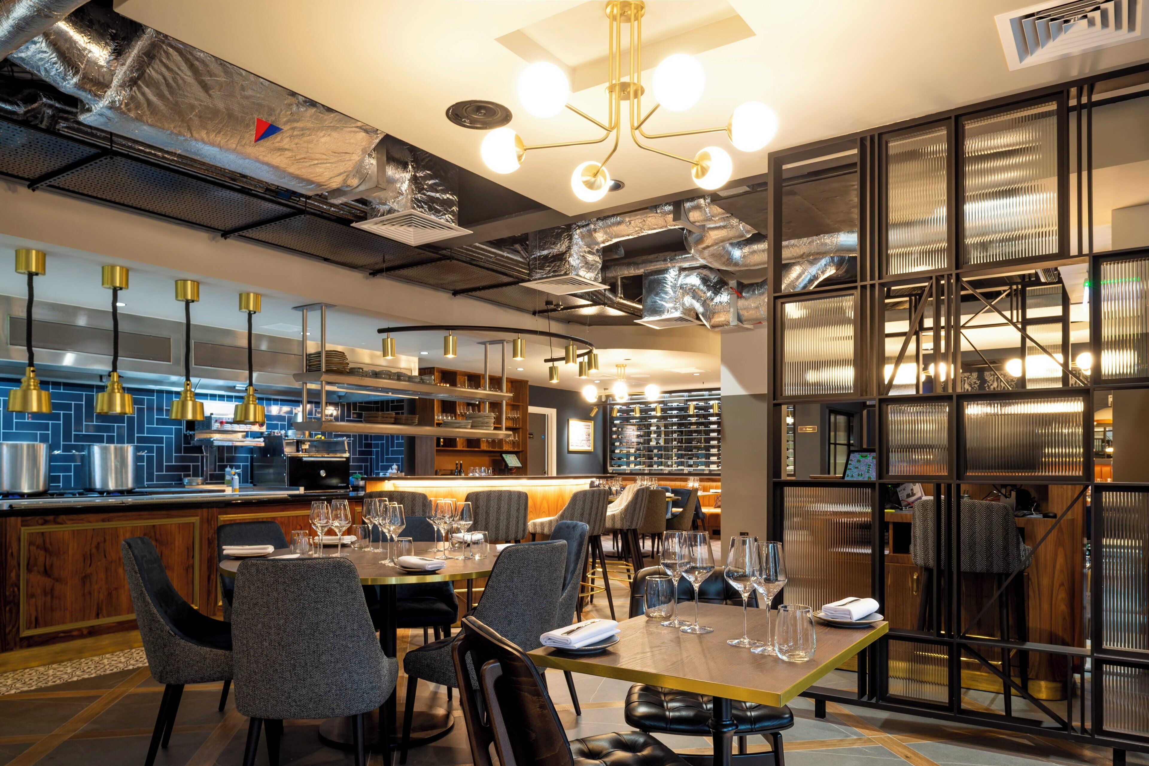 Ein modernes Restaurant-Interieur mit Barbereich, Esstischen und einer Weinauslage.