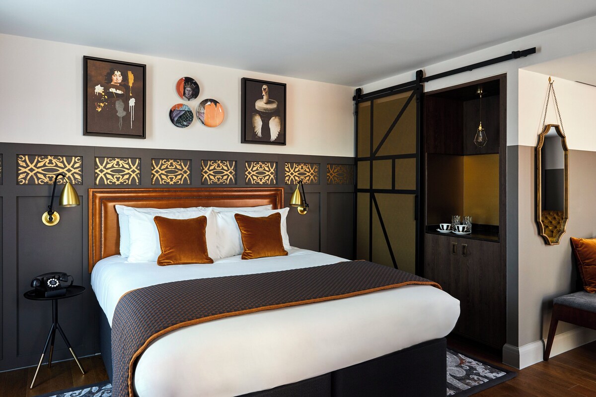 A modern bedroom with a large bed, decorative wall panels, a wardrobe, and a hanging light fixture.