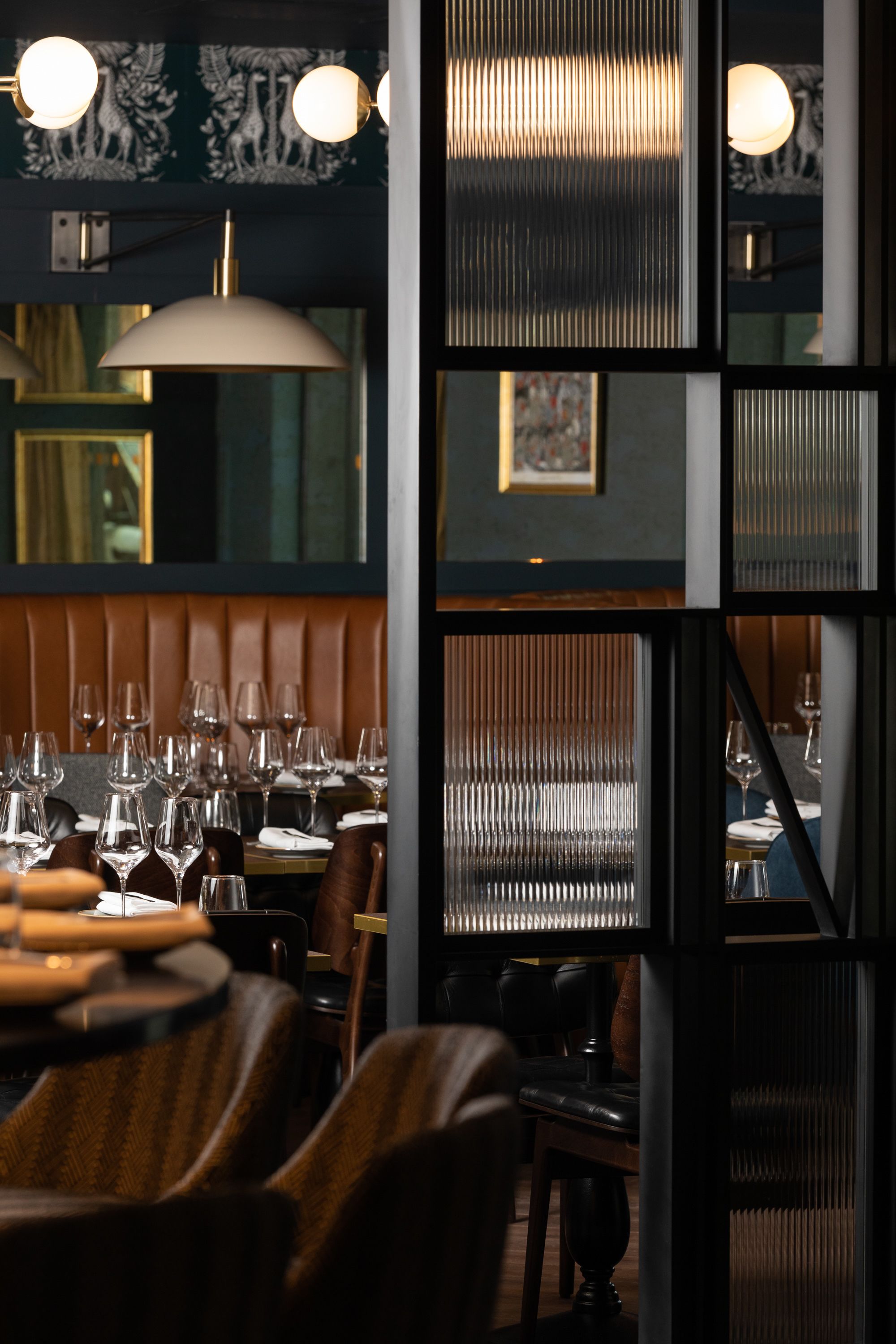 L’intérieur d’un restaurant, avec un espace repas, des tables, des chaises et un grand luminaire suspendu.