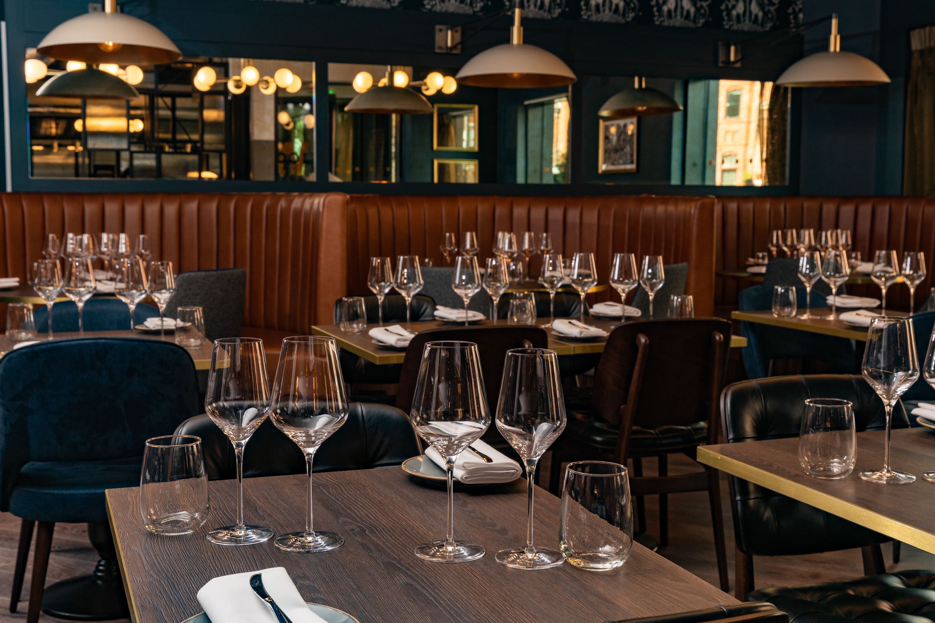 A restaurant with multiple tables set for dining, each with wine glasses and plates.