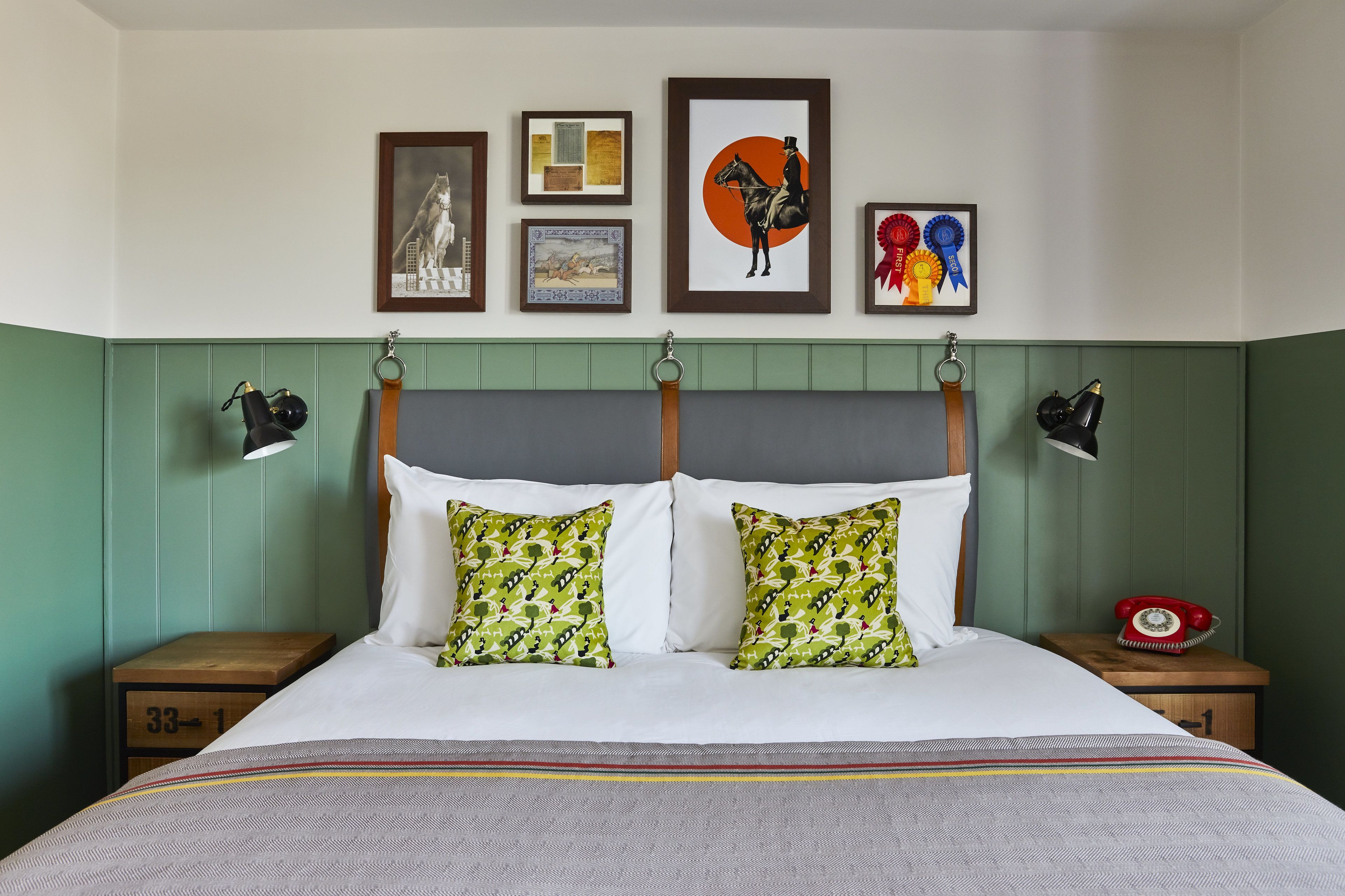A neatly arranged bedroom with a bed, two nightstands, a red rotary phone, and framed artwork on the wall.