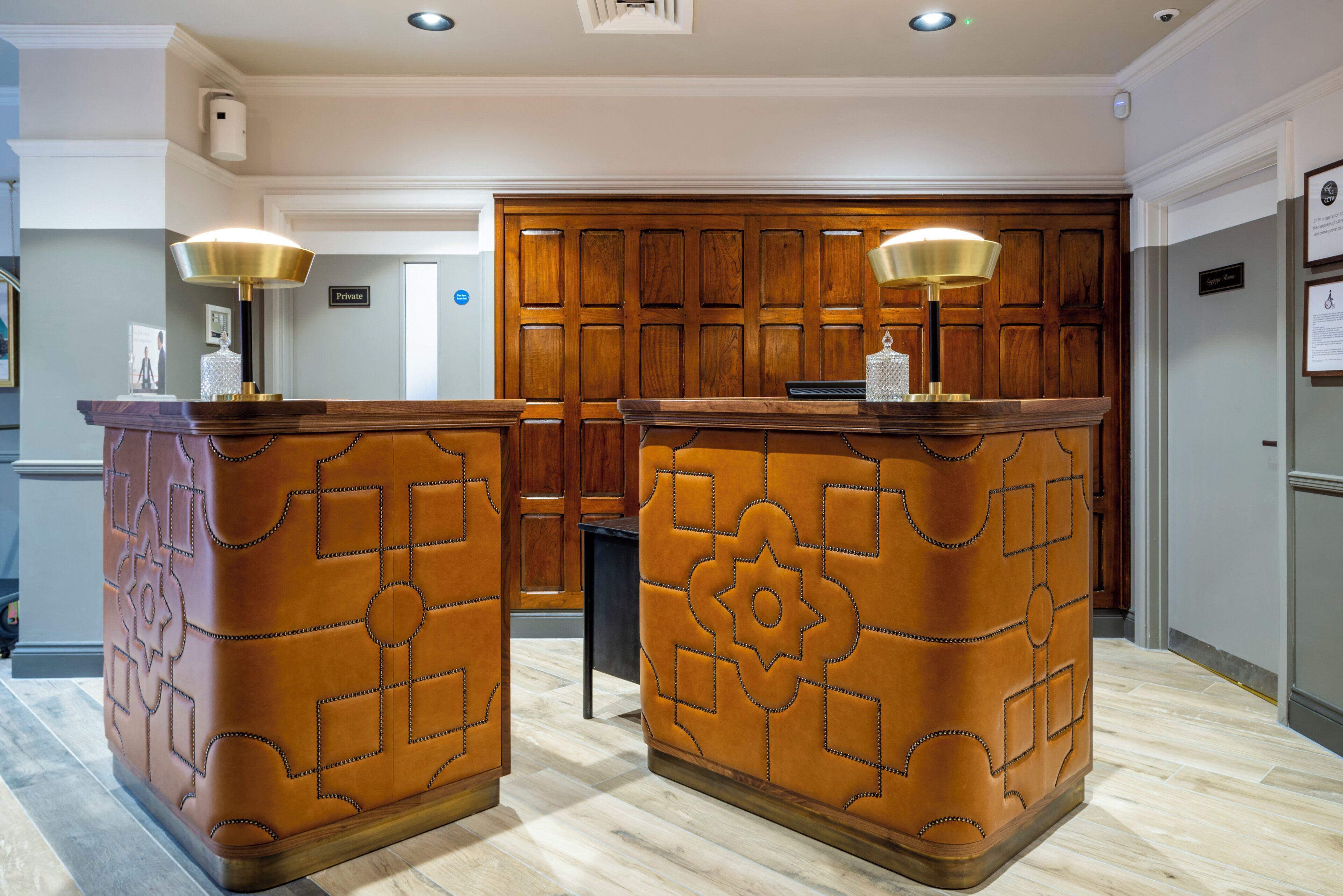 A reception area with two wooden reception desks, each with a lamp and a small decorative item.