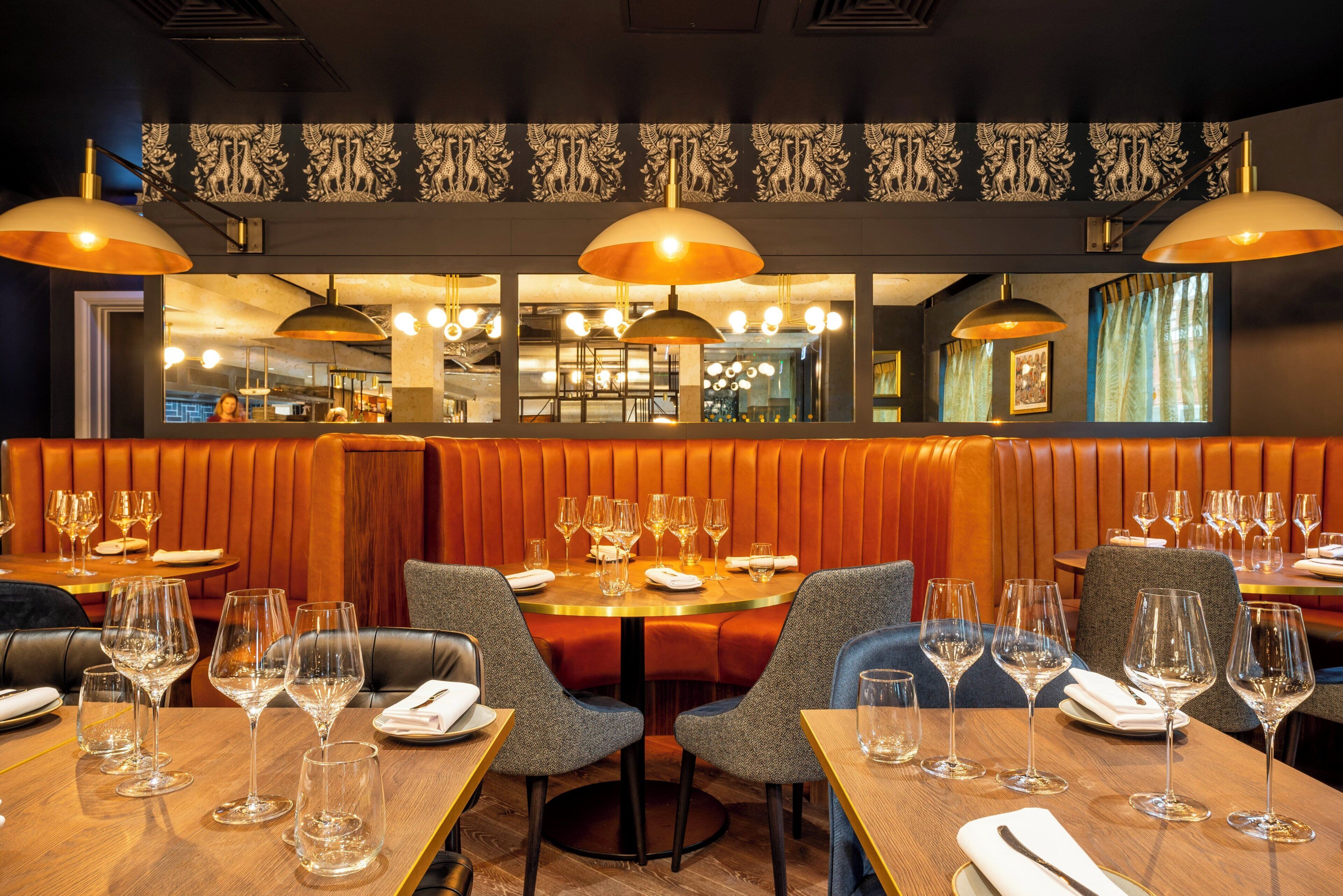 A restaurant interior with booths, tables, and hanging pendant lights.