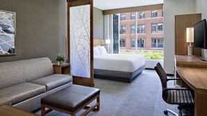 Una habitación de hotel con cama, sofá, escritorio y televisor.