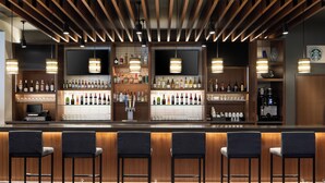 Una zona de bar con paneles de madera, varias estanterías llenas de botellas y taburetes.
