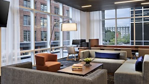 Un espacio lounge moderno con ventanas amplias, asientos cómodos y un televisor de pantalla plana.