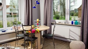 A dining area with a round table, chairs, and a window with curtains. - Viola Tricolor, Exclusive FW on North Beach, pure relaxation, hiking, biking (Nordstrand)