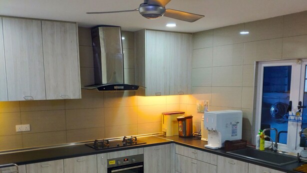 A modern kitchen with light wood cabinets, a stainless steel range, a built-in oven, and a ceiling fan. - Wawasan Homestay Butterworth (Butterworth)