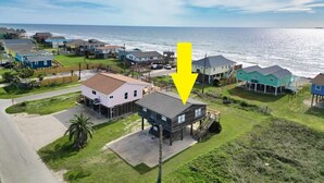An aerial view of a coastal residential area with houses, a road, and the ocean in the background. - Charming 2nd Row remodel with Beach Views (Surfside Beach)