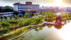 A hotel with a modern architectural design, a surrounding park, and a reflection pool.