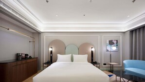 A modern hotel room with a large bed, bedside tables, a desk, and a chair.